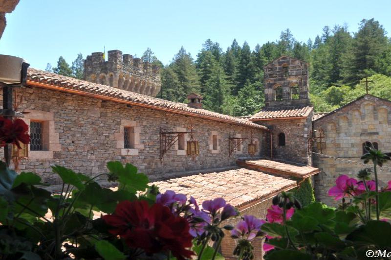 Castello Di Amorosa: каменные стены, черепица и цветы в тени леса